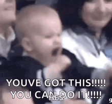 a baby is crying in a crowd of people and a woman is holding him .