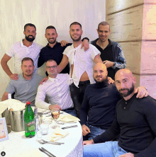 a group of men posing for a picture with a bottle of perrier water in the middle