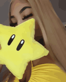 a woman in a yellow dress holds a yellow star pillow in front of her face