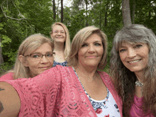four women posing for a picture with one wearing a pink cardigan