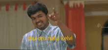 a man in a plaid shirt is pointing at the camera with the words " ithu oru nilla kelvi " written in yellow