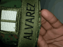 a person holding a military uniform with the name alvarez on it