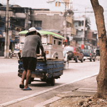 a man pushes a cart down a street in front of a building