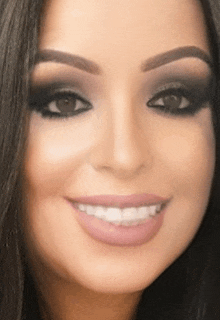 a close up of a woman 's face with makeup on and smiling