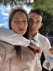 a man and a woman pose for a picture with a bottle of ioah water in the background