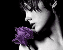 a black and white photo of a woman with a purple rose in her hand