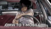 a woman is driving a car with the words `` omw to t-mobile !!! '' written on the steering wheel .