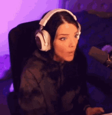 a woman wearing headphones and a hoodie is sitting in front of a microphone .