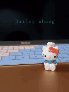 a hello kitty figurine sits on top of a macbook