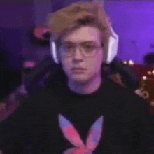 a young man wearing glasses and headphones is sitting in a chair in front of a computer screen .