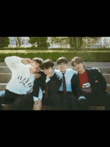 a group of young men are sitting on a bench together .
