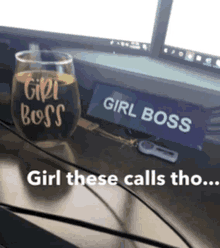 a wine glass that says girl boss sits on a desk next to a sign that says girl boss