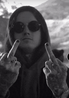 a person wearing sunglasses and a hood giving the middle finger