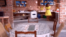 a woman in a yellow dress is standing in a kitchen next to a table and chairs