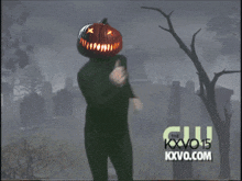 a man with a pumpkin on his head is dancing in a cemetery with the kxvo15 logo