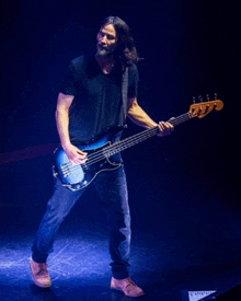 a man is playing a blue bass guitar on a stage