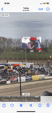 a phone screen shows a picture of a race track and the time of 8:34