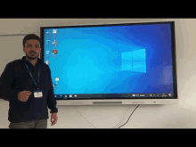 a man is standing in front of a large interactive whiteboard .