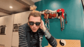 a man wearing sunglasses and a ponytail stands in front of a zebra statue
