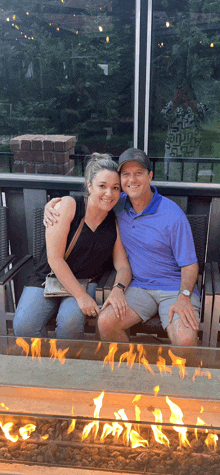 a man and a woman are sitting in front of a fire pit