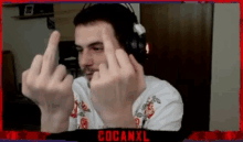 a man wearing headphones is giving the middle finger in front of a red frame that says cocanxl