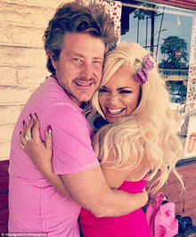 a woman in a pink dress is hugging a man with a beard