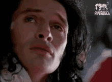 a man with long hair is crying with a tear coming out of his eye .