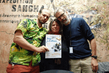 three people pose for a photo in front of a sign that says sangha on it