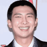 a man with a shaved head is smiling for the camera while wearing a suit and tie .