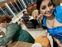 a man in a suit sits at a table in a diner while two women pose for a picture