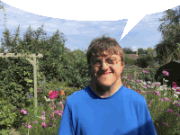 a man wearing glasses and a blue shirt is standing in front of flowers