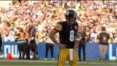 a football player wearing a number 8 jersey stands on the field