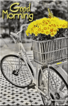 a black and white photo of a bicycle with a basket full of yellow flowers and the words good morning above it