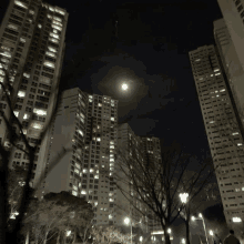 a full moon is visible behind a tall building