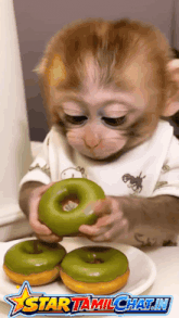 a monkey is holding a green donut in front of a plate of donuts