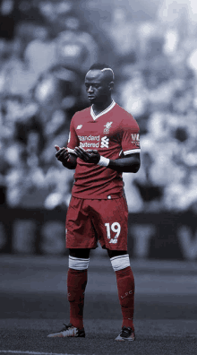 a soccer player wearing a red jersey that says standard chartered