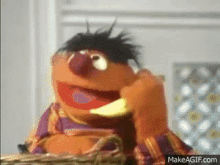 a close up of ernie from sesame street eating a banana on makeagif.com