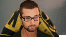 a man with glasses and a beard is sitting in a chair