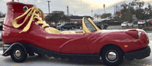 a red car that looks like a shoe is parked in a parking lot next to a mcdonald 's