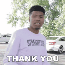 a young man in a purple shirt is standing in front of a white car and says thank you .