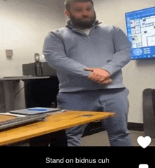 a man standing in front of a desk with the words stand on bidnus cuh