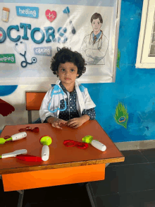 a little girl dressed as a doctor is sitting at a desk