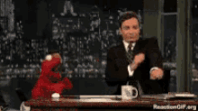 a man in a suit and tie is sitting at a desk with elmo on it