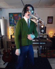 a man in a green sweater is singing into a microphone in a room