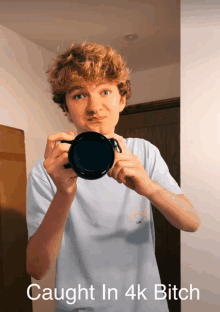 a young man holding a camera with the words caught in 4k bitch on the bottom