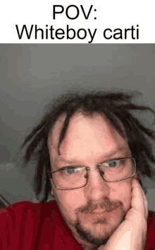 a man with dreadlocks and glasses is wearing a red sweater and a red shirt .