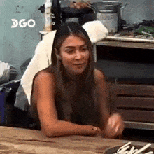 a woman is sitting at a table in a kitchen with a plate of food in front of her .