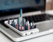 a cell phone with a city skyline on it is sitting on top of a laptop computer .