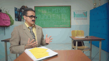 a man sitting at a desk in front of a chalkboard that says del mismo modo en el sentido contrario