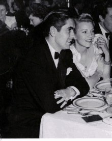 a man and a woman are sitting at a table with plates and glasses .